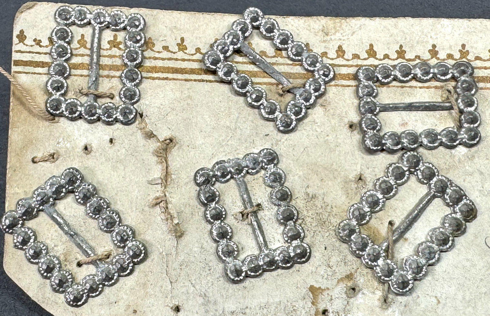 Antique stamped cut steel look silvertone pot metal miniature sliding belt buckles. Lot of 6.: Antique stamped cut steel look silvertone pot metal miniature sliding belt buckles. Lot of 6. Unused in cardboard. Original with no prong. Unmarked . For measures please refer to the pictures taken wi