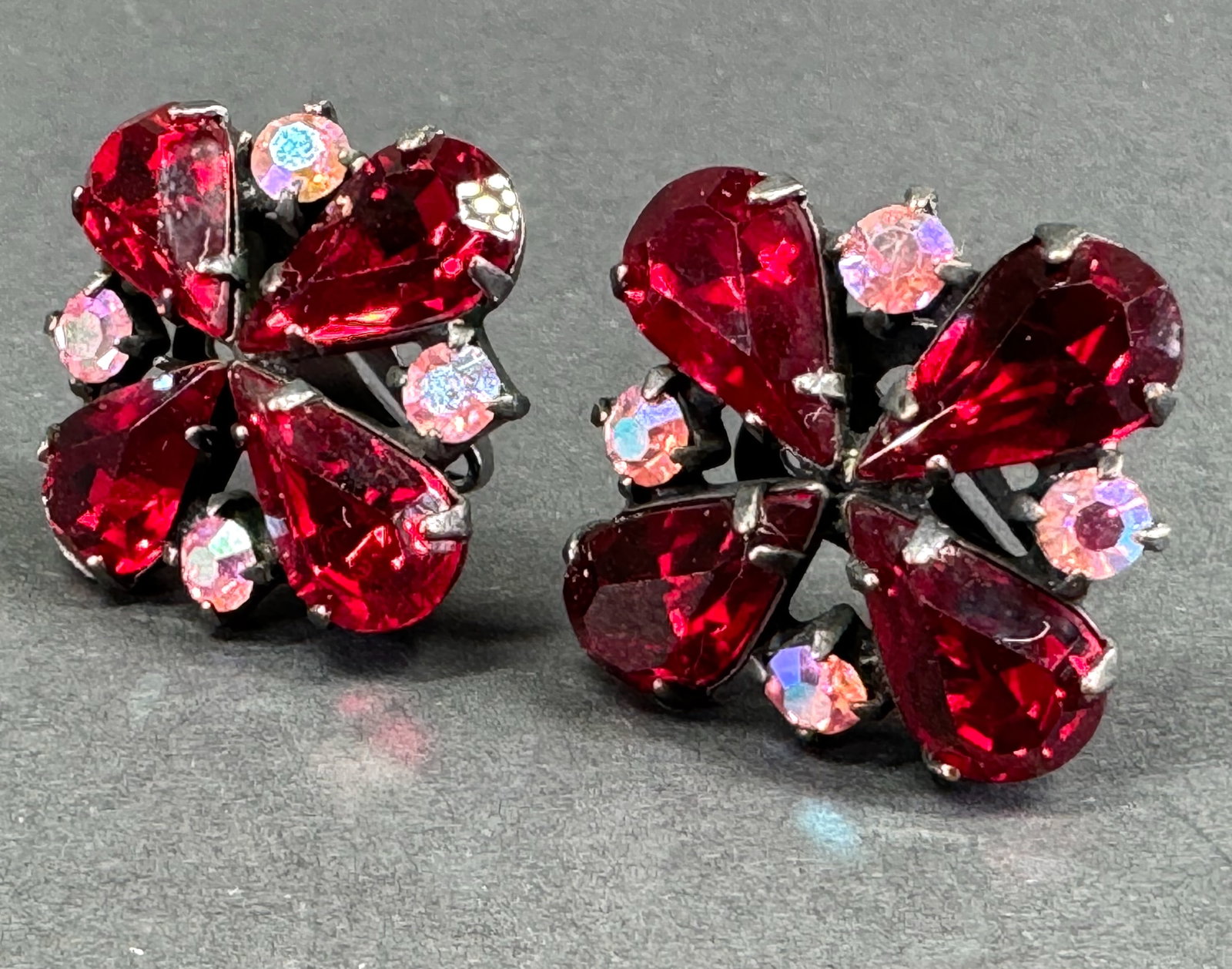 Vintage AB & ruby color crystals japanned metal clip on earrings.: Vintage AB & ruby color crystals japanned metal clip on earrings. Unmarked. For measures please refer to the pictures taken with a measuring tape. Weight: 11 Grams. This is a NO RESERVE AUCTION: there