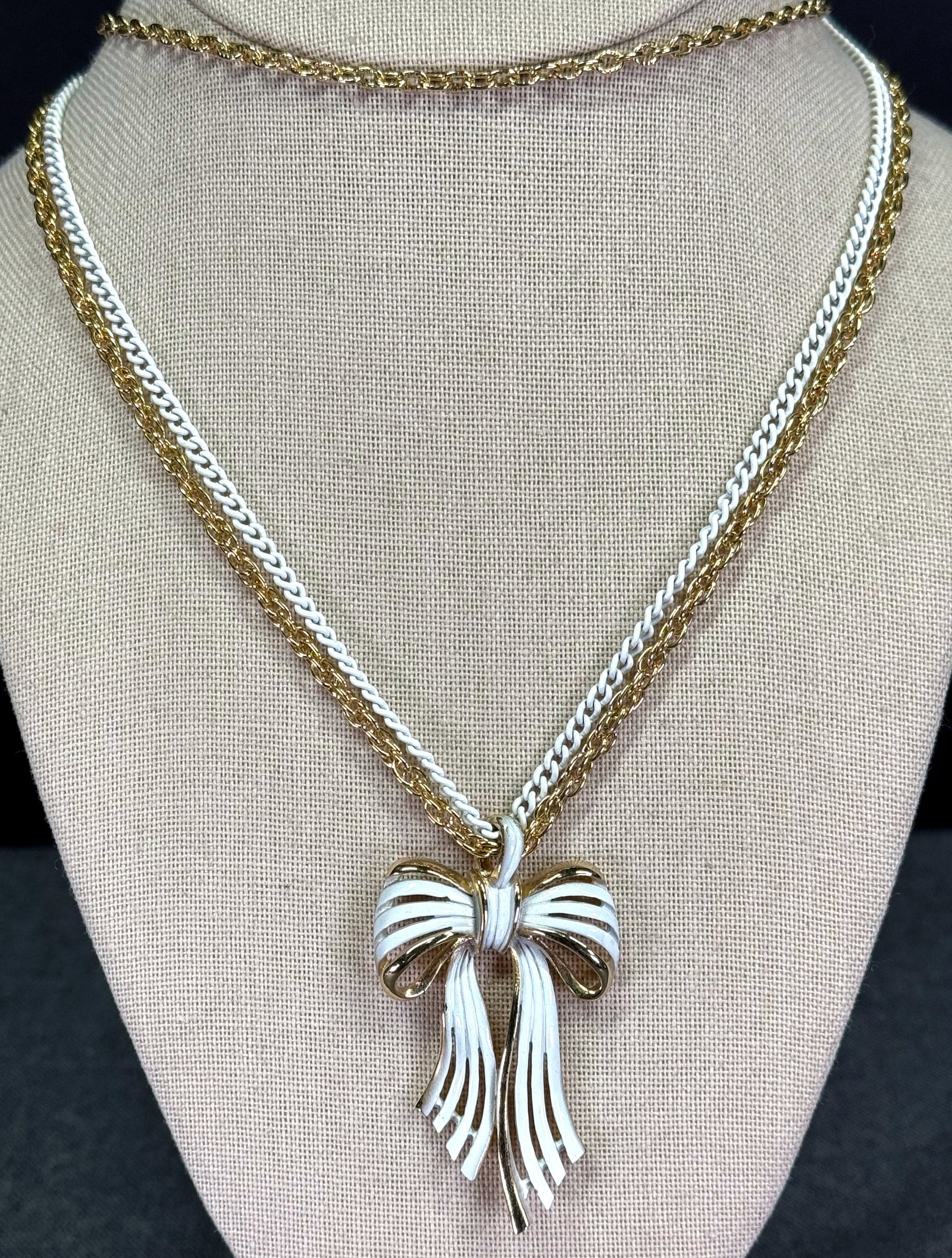 Vintage 80s white enamel goldtone metal ribbons in bow pendant chained necklace: Vintage 80s white enamel goldtone metal ribbons in bow pendant chained necklace. Unmarked. For measures please refer to the pictures taken with a measuring tape. Weight: 39 Grams. IN HOUSE Estimated* 