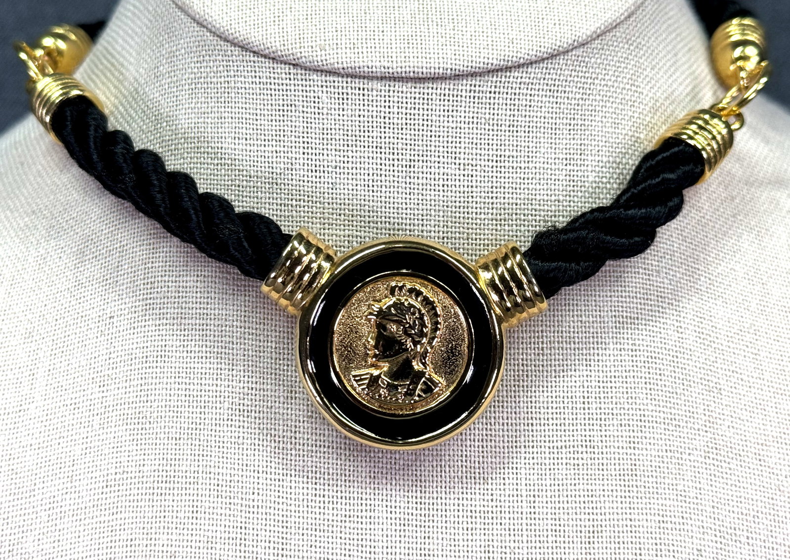 Vintage 80s goldtone metal black silky cord enamel warrior medallion necklace: Vintage 80s goldtone metal black silky cord enamel warrior medallion necklace. Unmarked. For measures please refer to the pictures taken with a measuring tape. Weight: 42 Grams. IN HOUSE Estimated* sh