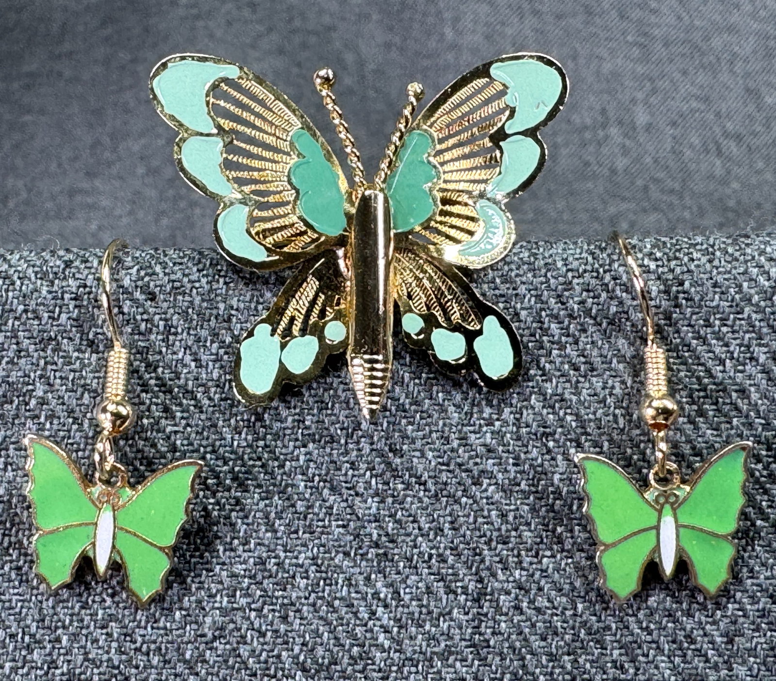 Vintage green enamel goldtone metal butterfly hook earrings and pin brooch: Vintage green enamel goldtone metal butterfly hook earrings and pin brooch. Unmarked. For measures please refer to the pictures taken with a measuring tape. Weight: 5 Grams. IN HOUSE Estimated* shippi