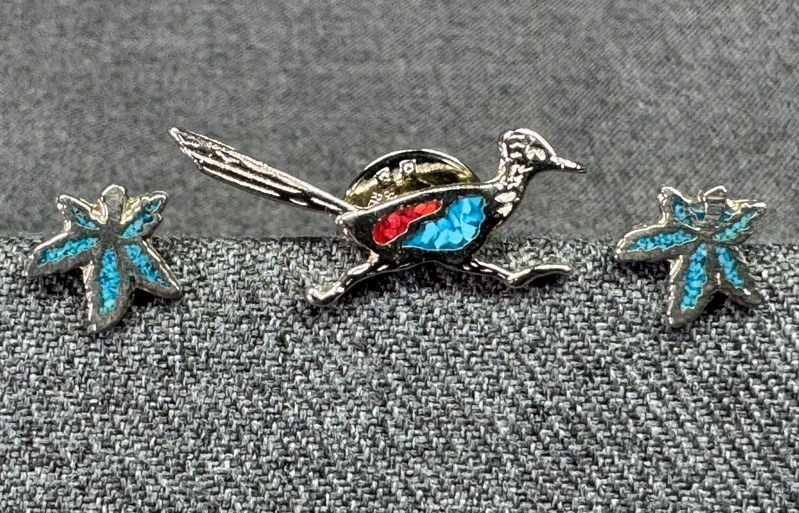 Vintage turquoise inlay silvertoned metal roadrunner lapel pin and leaf stud earrings: Vintage turquoise inlay silvertoned metal roadrunner lapel pin and leaf stud earrings. Unmarked. For measures please refer to the pictures taken with a measuring tape. Weight: 3 Grams IN HOUSE Estimat