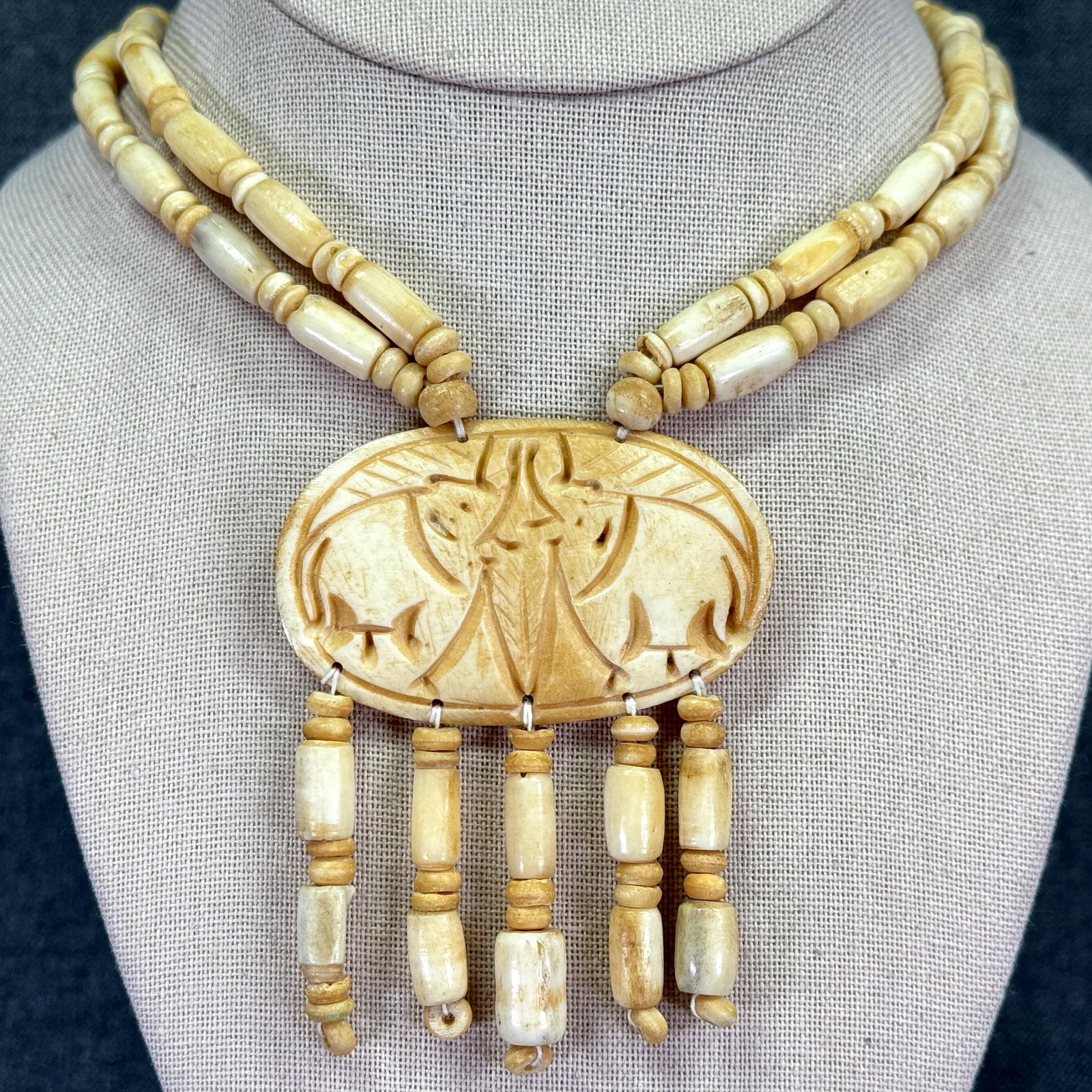 Vintage carved elephant lovers medallion with tassels beaded bone necklace: Vintage carved elephant lovers medallion with tassels beaded bone necklace. Unmarked. For measures please refer to the pictures taken with a measuring tape. Weight: 43 Grams. IN HOUSE Estimated* shipp