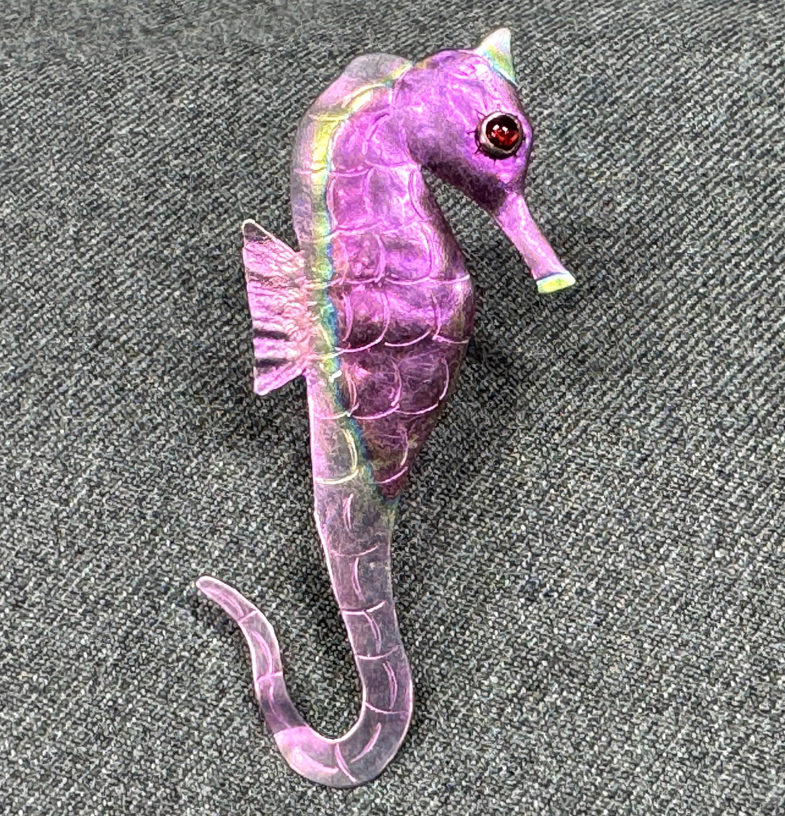 Vintage artsy garnet eye embossed and anodized niobium seahorse brooch pin: Vintage artsy garnet eye embossed and anodized niobium seahorse brooch pin. Unmarked. For measures please refer to the pictures taken with a measuring tape. Weight: 4 Grams. IN HOUSE Estimated* SHIPPI