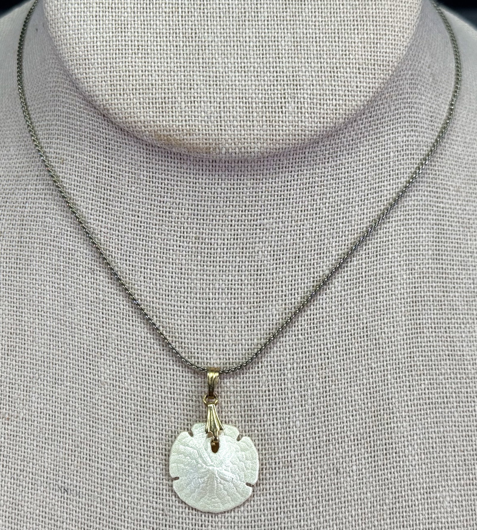 Vintage golden bail miniature pearly sand dollar pendant with silvertone metal snake chain: Vintage golden bail miniature pearly sand dollar pendant with silvertone metal snake chain . Unmmarked. For measures please refer to the pictures taken with a measuring tape. Weight: 4 Grams. This is 