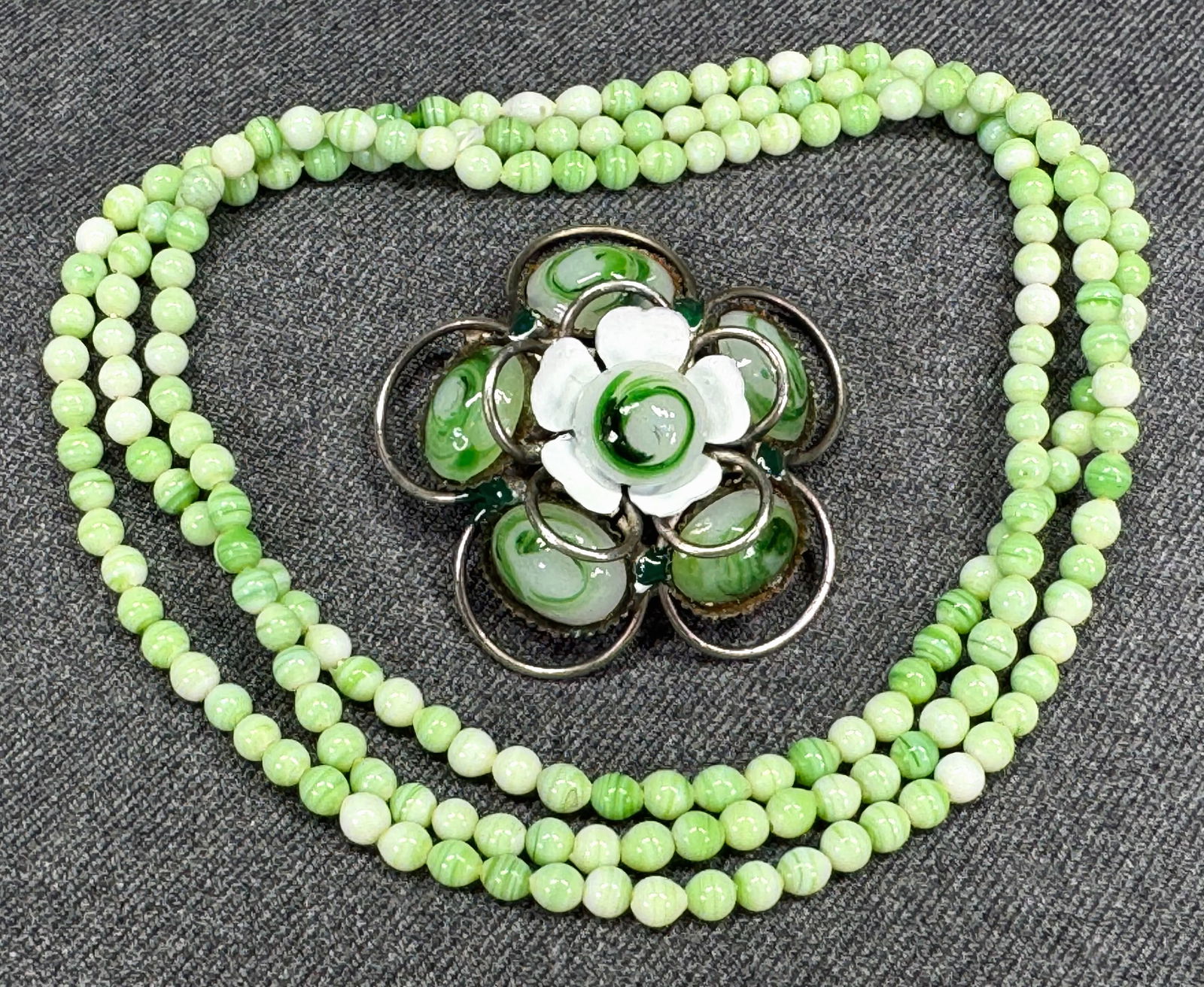 Vintage enamel marbled glass silvertone flower brooch & green glass beads necklace: Vintage white enamel marbled greenish milky glass silvertone metal flower pin brooch & marbled green glass beaded no clasp necklace. Unmarked. For measures please refer to the pictures taken with a me