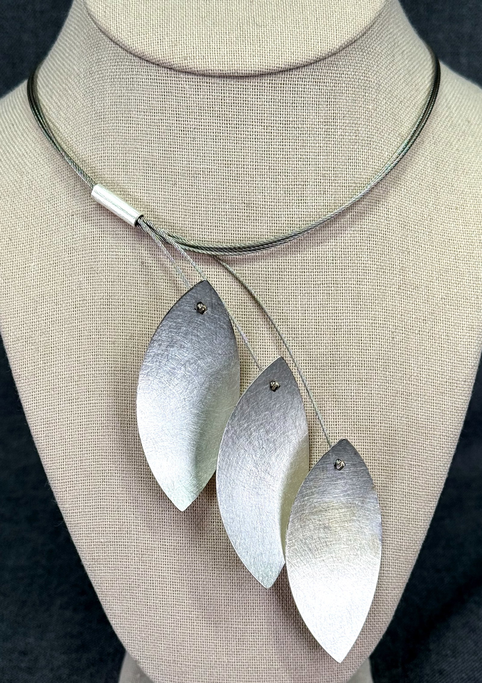 Artsy silver wire dangling three brushed leaves choker necklace.: Artsy silvertoned metal wire dangling three brushed leaves choker necklace. Marked 925 sterling clasp. For measures please refer to the pictures taken with a measuring tape. Weight: 120 Grams. IN HOUS