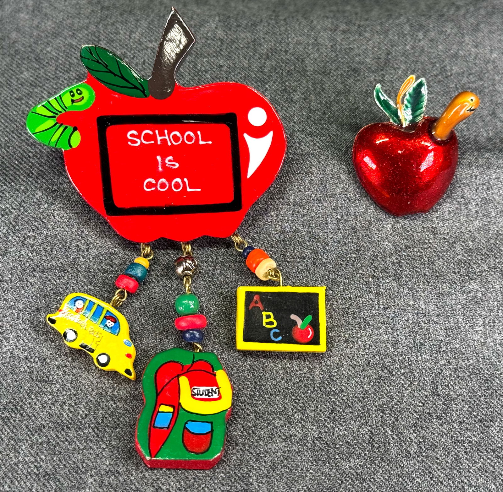 Vintage apple with worm pin brooches AAI enamel metal & School is Cool wooden with dangles: Vintage apple with worm pin brooches. Ennamel metal marked AAi & unbranded School is Cool wooden with dangles. For measures please refer to the pictures taken with a measuring tape. Weight: 25 Grams.