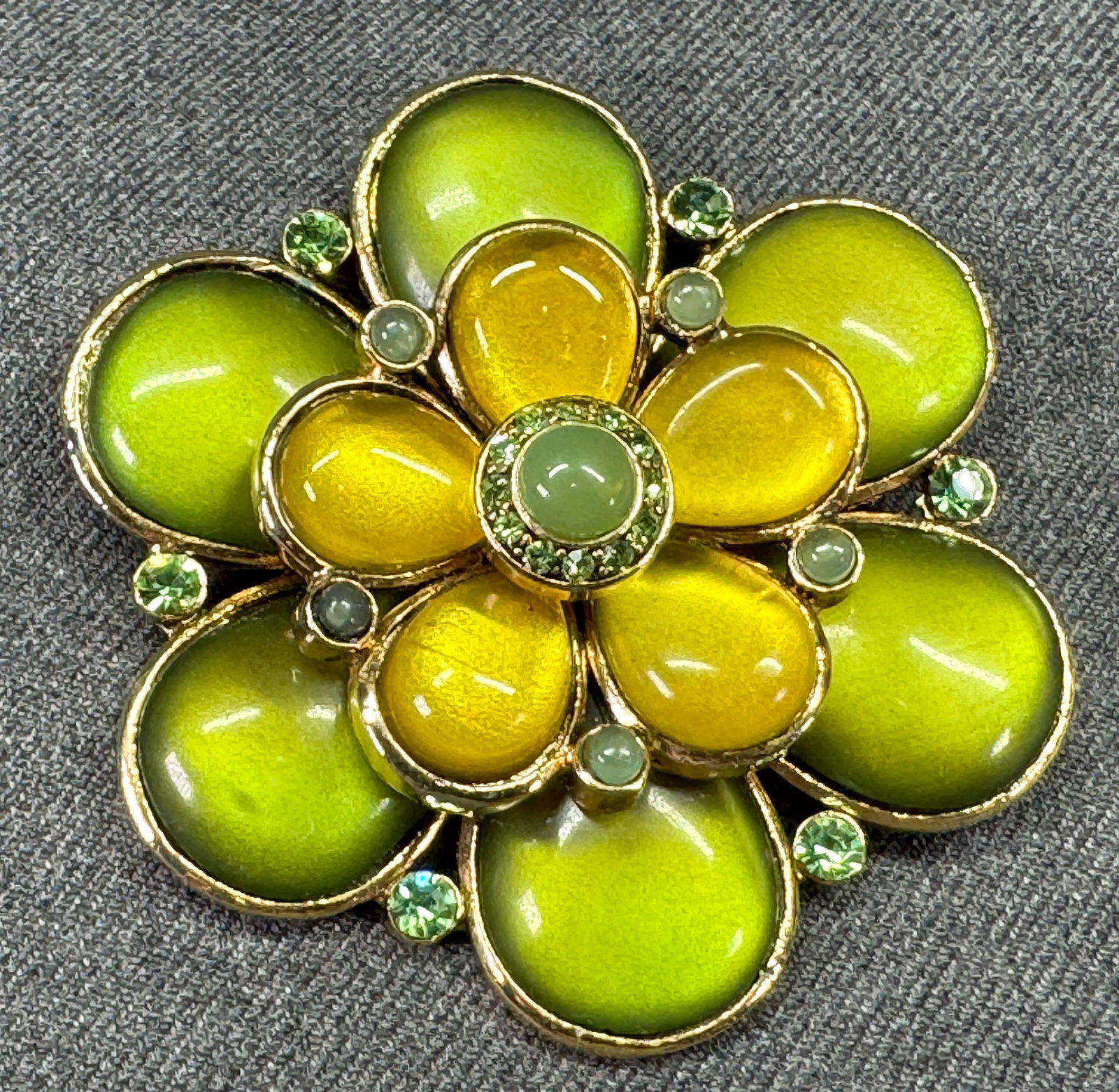 Vintage greenish rhinestones & lucite cabs goldtoned flower brooch pin: Vintage greenish rhinestones & lucite cabs goldtoned flower brooch pin. Unmarked. For measures please refer to the pictures taken with a measuring tape. Weight: 60 Grams. IN HOUSE Estimated* SHIPPING 