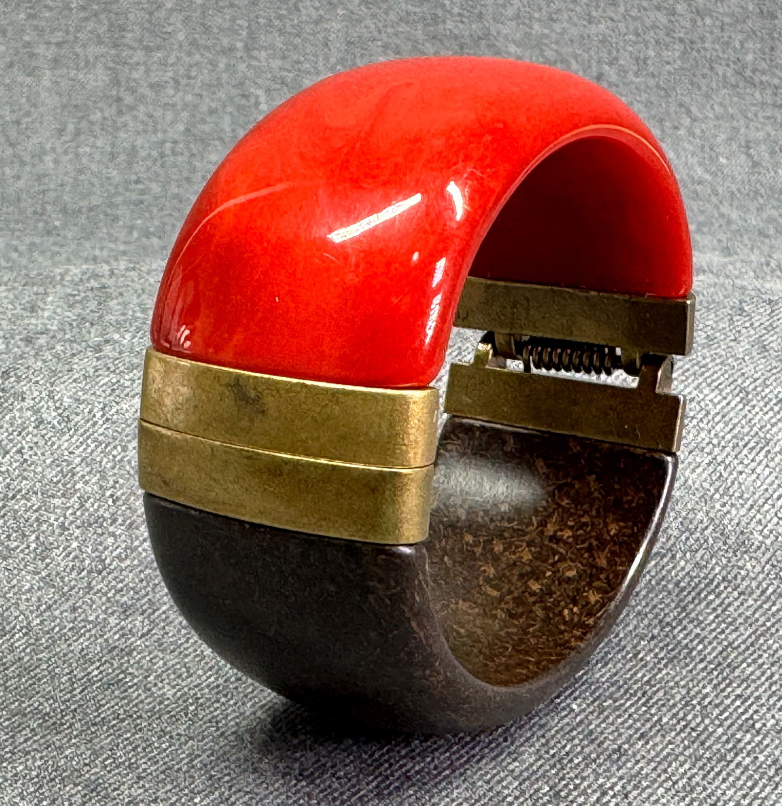 Bakelite like and wooden like plastic hinged bracelet: Bakelite like and wooden like plastic hinged bracelet. Brass antiqued like metal. Unmarked. For measures please refer to the pictures taken with a measuring tape. Weight: 64 Grams. IN HOUSE Estimated*