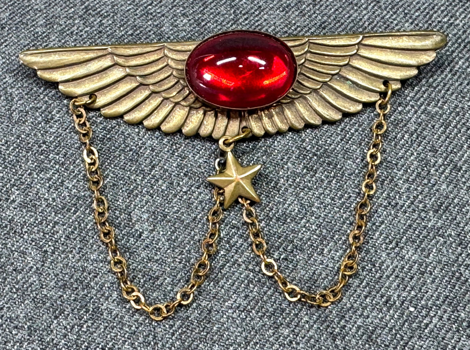 Vintage military red glass cab wings with star dangle brooch pin: Vintage military red glass cab goldtoned metal wings with star dangle brooch pin. Unmarked. For measures please refer to the pictures taken with a measuring tape. Weight: 12 grams.< IN HOUSE Estimated