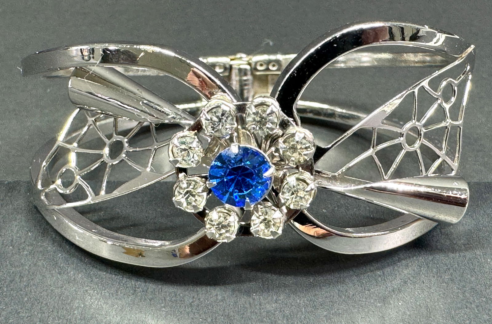 Vintage clear & blue crystals flower filigree silvertone metal hinge bracelet.: Vintage clear & blue crystals flower filigree silvertone metal hinge bracelet. Unmarked. For measures please refer to the pictures taken with a measuring tape. Weight: 25 Grams. This is a NO RESERVE A