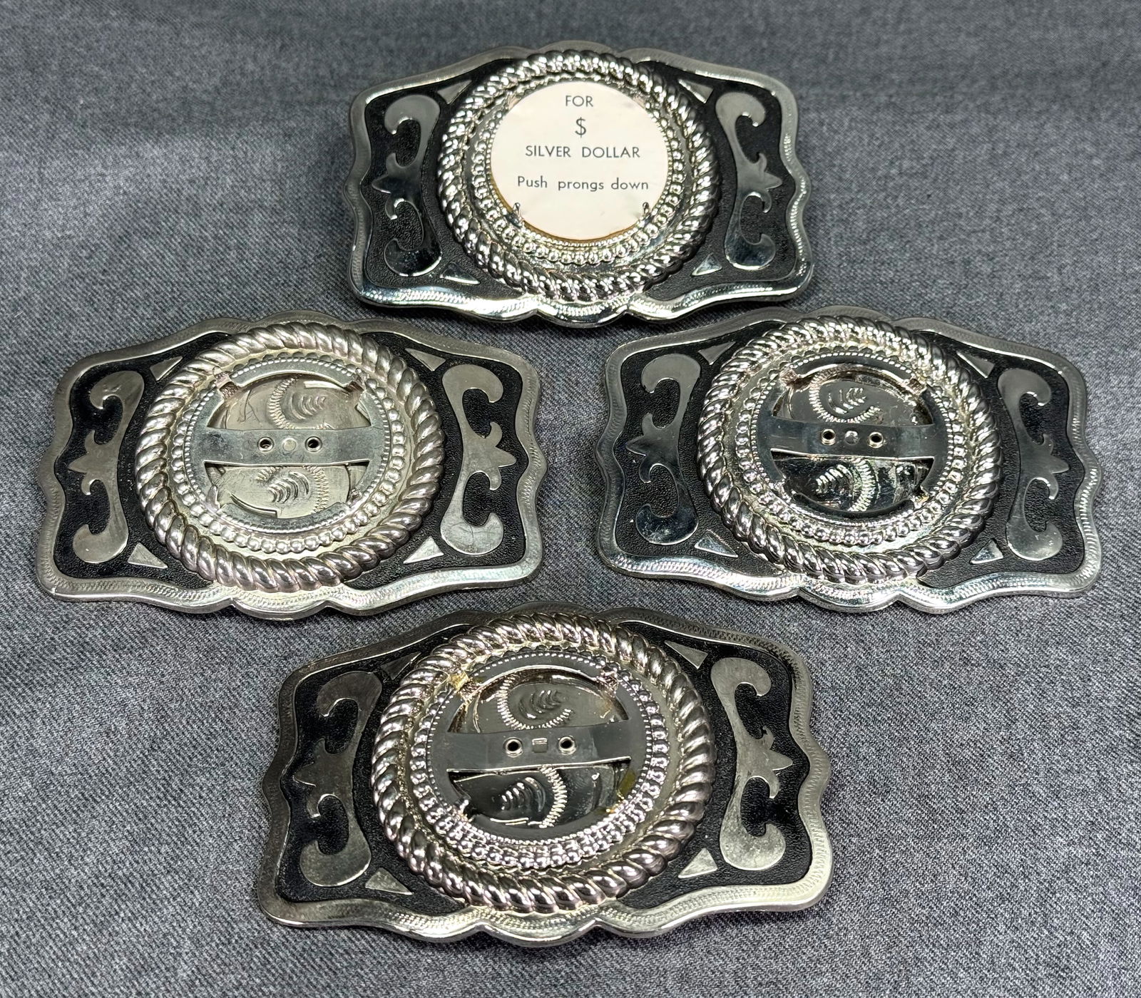 Vintage Western black paint silvertone metal insert a Silver Dollar heavy belt buckle. Lot of 4: Vintage Western black paint silvertone metal insert a Silver Dollar heavy belt buckle. Lot of 4. Unmarked. For measures please refer to the picture taken with a measuring tape. Weight: 400 Grams. IN H