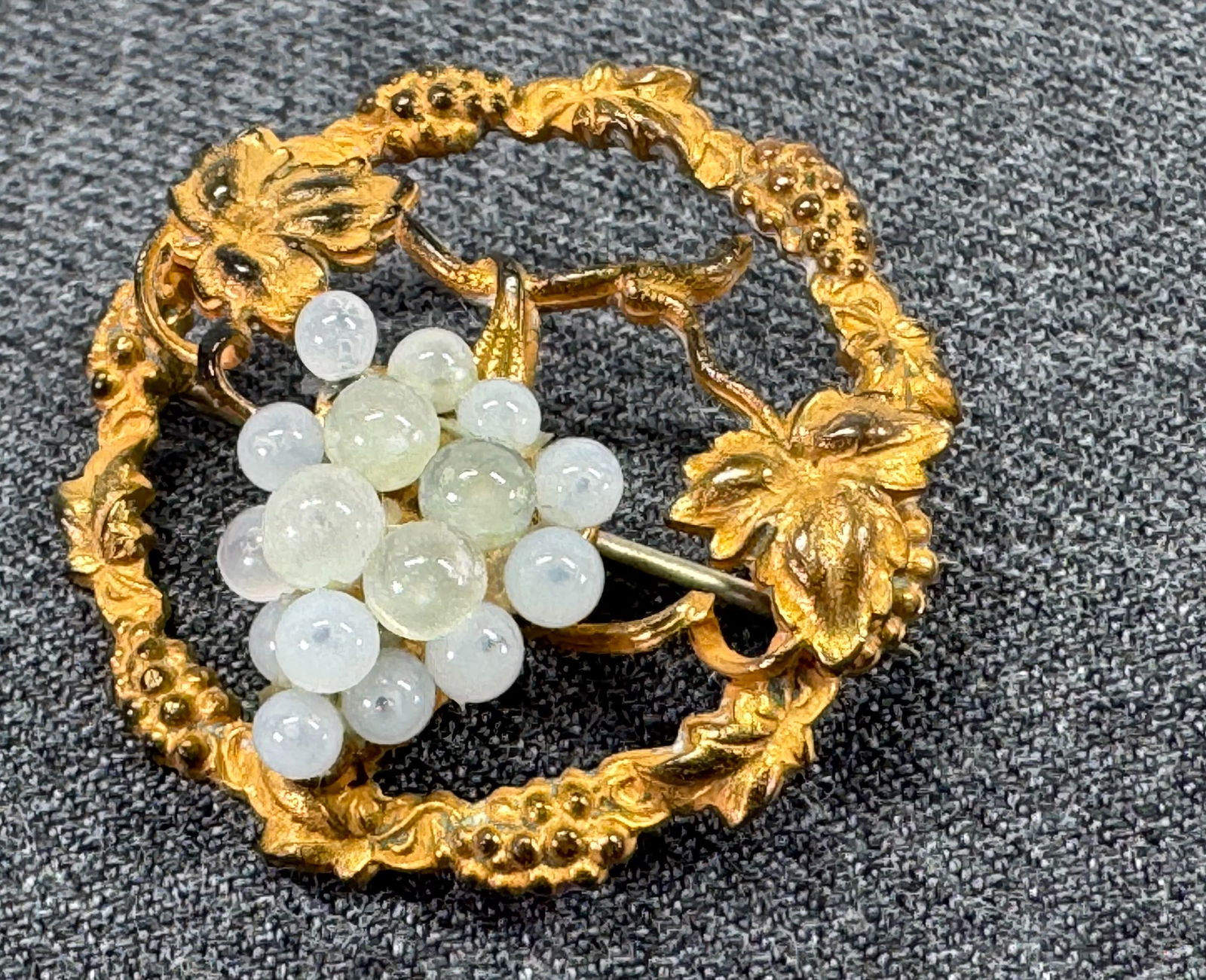 Antique whitish glass beaded grape cluster goldtoned vine branch brooch pin: Antique whitish glass beaded grape cluster goldtoned vine branch brooch pin. Unmarked . For measures please refer to the pictures taken with a measuring tape. Weight: 7 Grams. IN HOUSE Estimated* SHIP