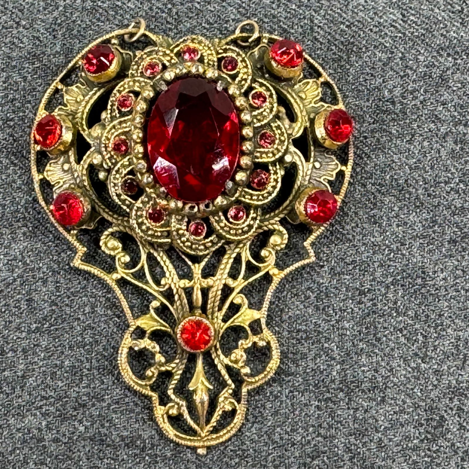 Antique Czech ruby color crystals goldtoned filigree medallion: Antique Czech ruby color crystals goldtoned filigree medallion. Two rings on top . Unmarked . For measures please refer to the pictures taken with a measuring tape. Weight: 20 Grams. IN HOUSE Estimate