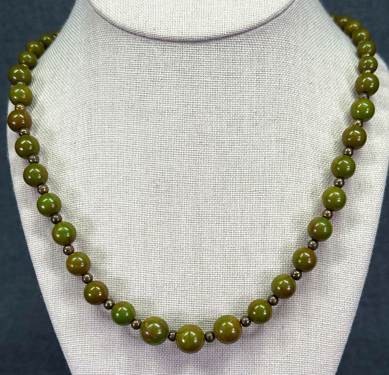 Vintage swirl spinach green bakelite & gold-toned metal beaded necklace: Vintage swirl spinach green bakelite & gold-toned metal beaded necklace. Unmarked. For measures please refer to the pictures taken with a measuring tape. Weight: 21 Grams IN HOUSE Estimated* SHIPPING