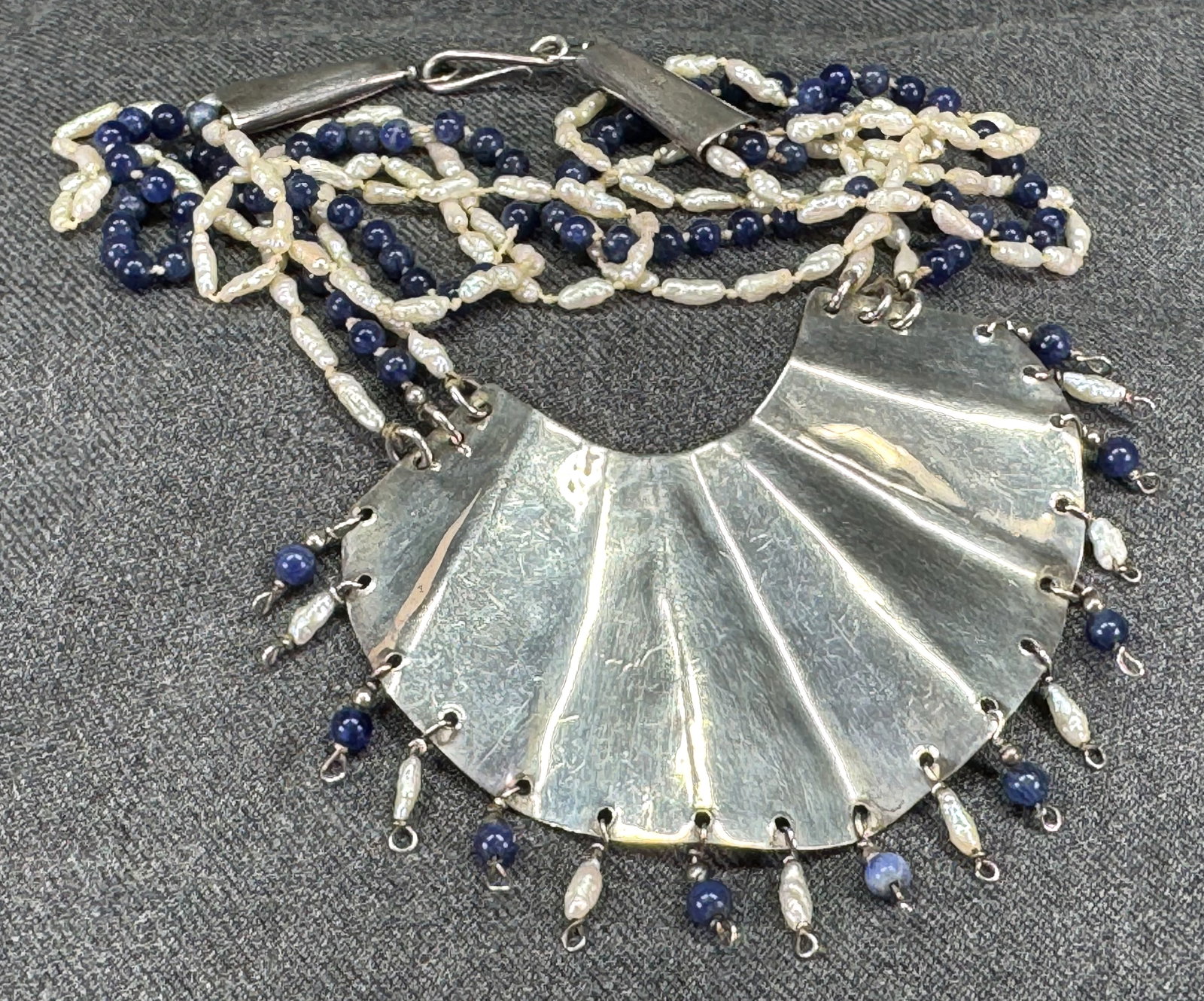 Vintage artsy lapis & baroque pearls sterling necklace. Marked Nanette & a flower: Vintage artsy lapis & baroque pearls beads sterling necklace. Pleated pendant with dangles. Three strands with hand knotted in between beads. Marked Nanette & a flower. For measures please refer to th