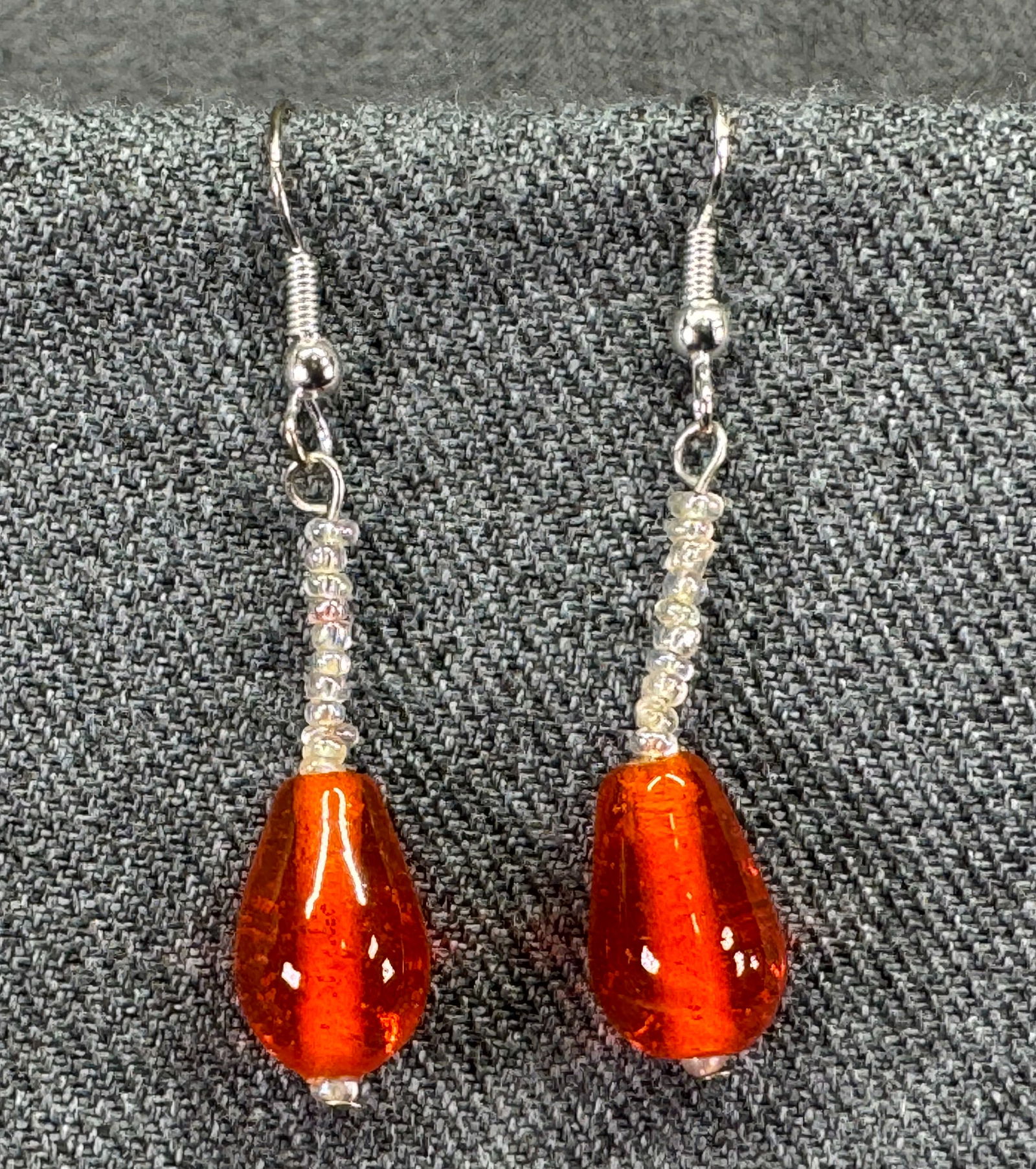 Orange & clear glass silver-toned hook earrings: Orange & clear glass silver-toned hook earrings. Unmarked . For measures please refer to the pictures taken with a measuring tape. Weight: 5 Grams. IN HOUSE FLAT SHIPPING & HANDLING COST WITHIN ALL TH