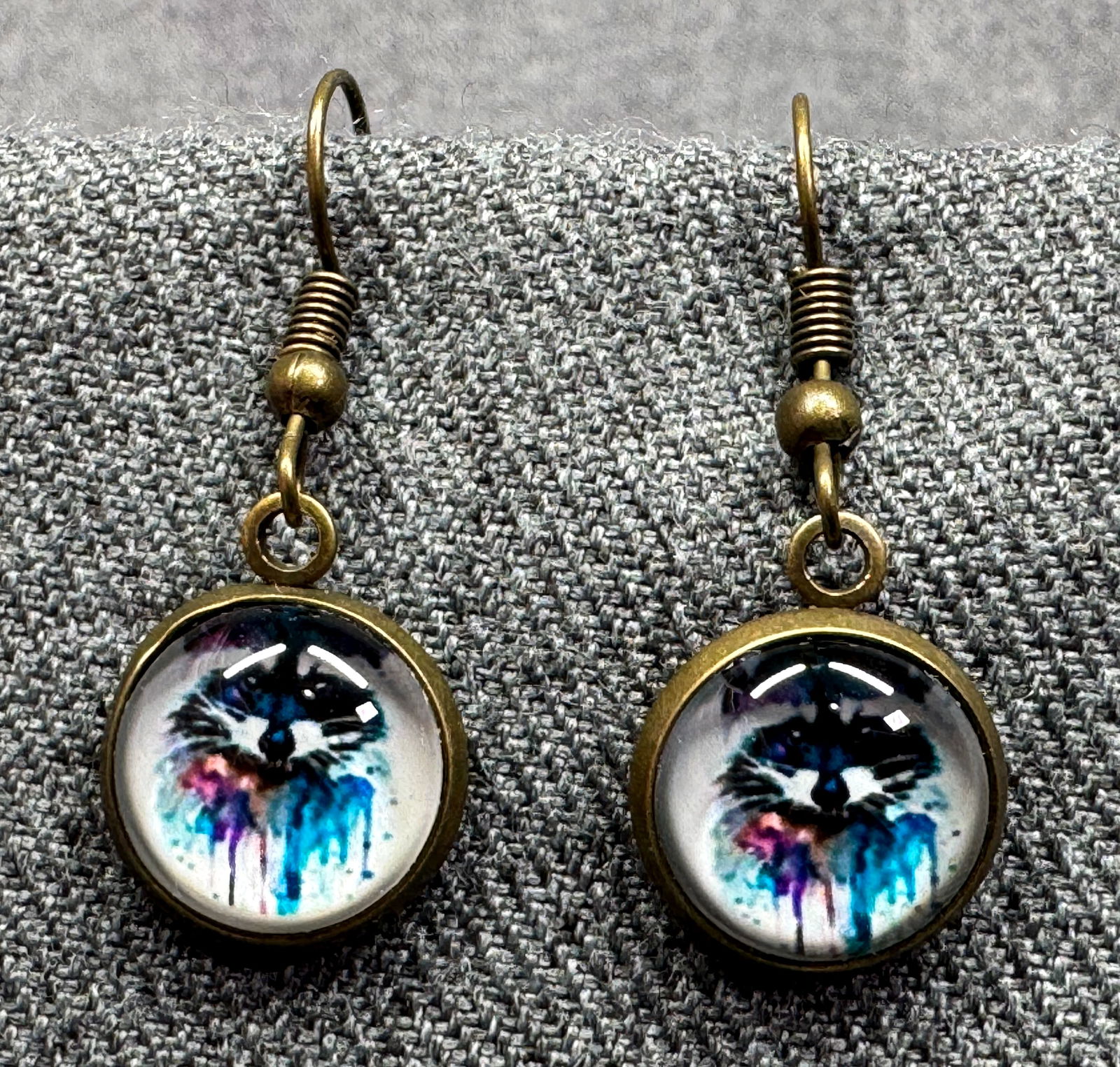 Vintage boho racoon dangle hook earrings. Dome clear glass & bronze-toned metal: Vintage boho racoon dangle hook earrings. Dome clear glass & bronze-toned metal. Unmarked. For measures please refer to the pictures taken with a measuring tape. Weight: 3 Grams. IN HOUSE FLAT SHIPPIN