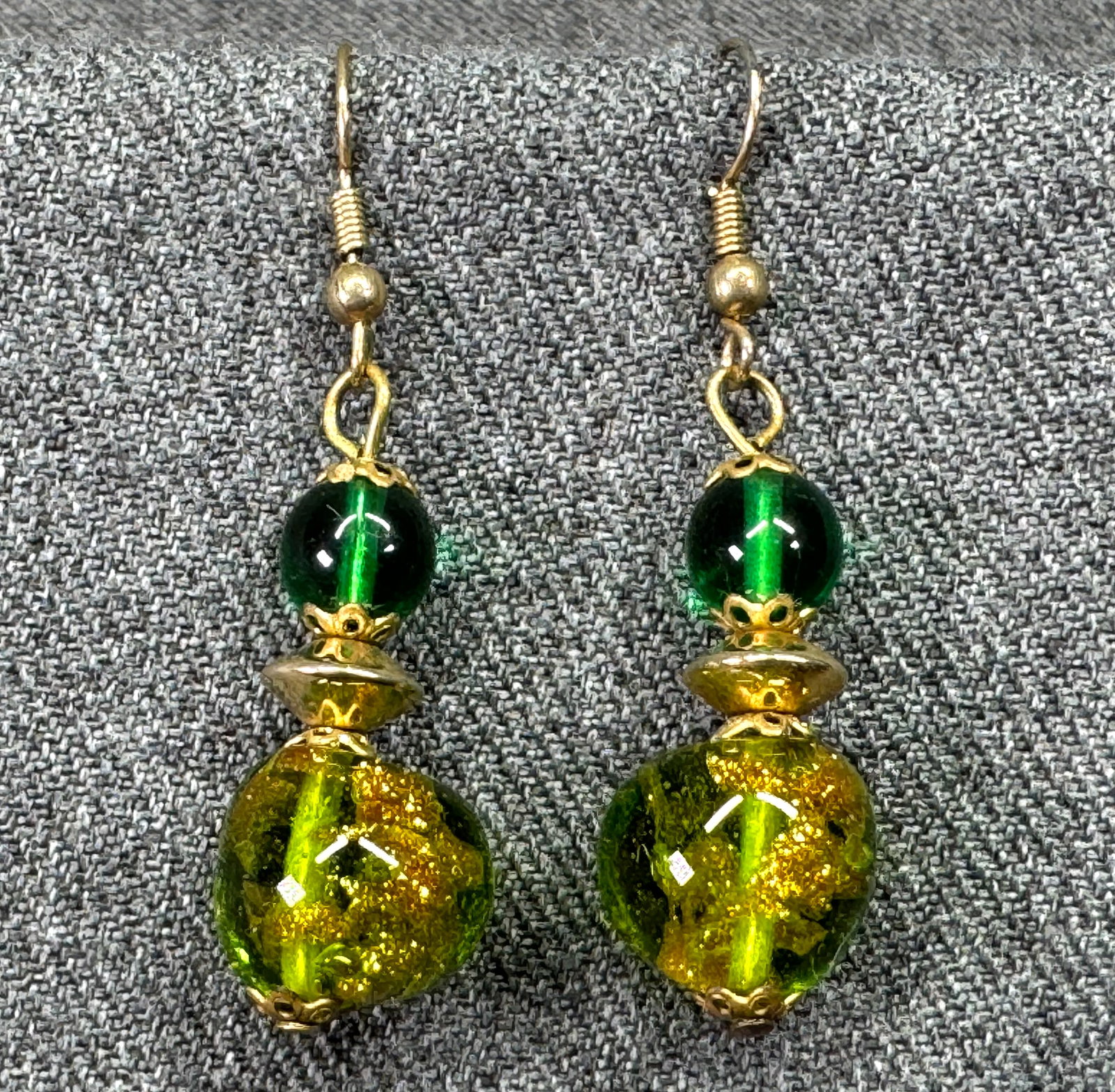 Vintage green glass gold-toned hook earrings: Vintage green glass gold-toned hook earrings. Unmarked. For measures please refer to the pictures taken with a measuring tape. Weight: 9 Grams. IN HOUSE FLAT SHIPPING & HANDLING COST WITHIN ALL THE U.