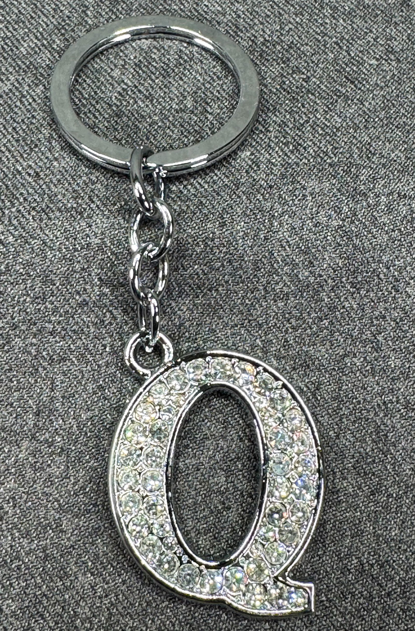 Initial letter Q clear crystals silver-toned metal key ring: Initial letter Q clear crystals silver-toned metal key ring. Unmarked. For measures please refer to the pictures taken with a measuring tape. Weight: 18 Grams. IN HOUSE FLAT SHIPPING & HANDLING COST W