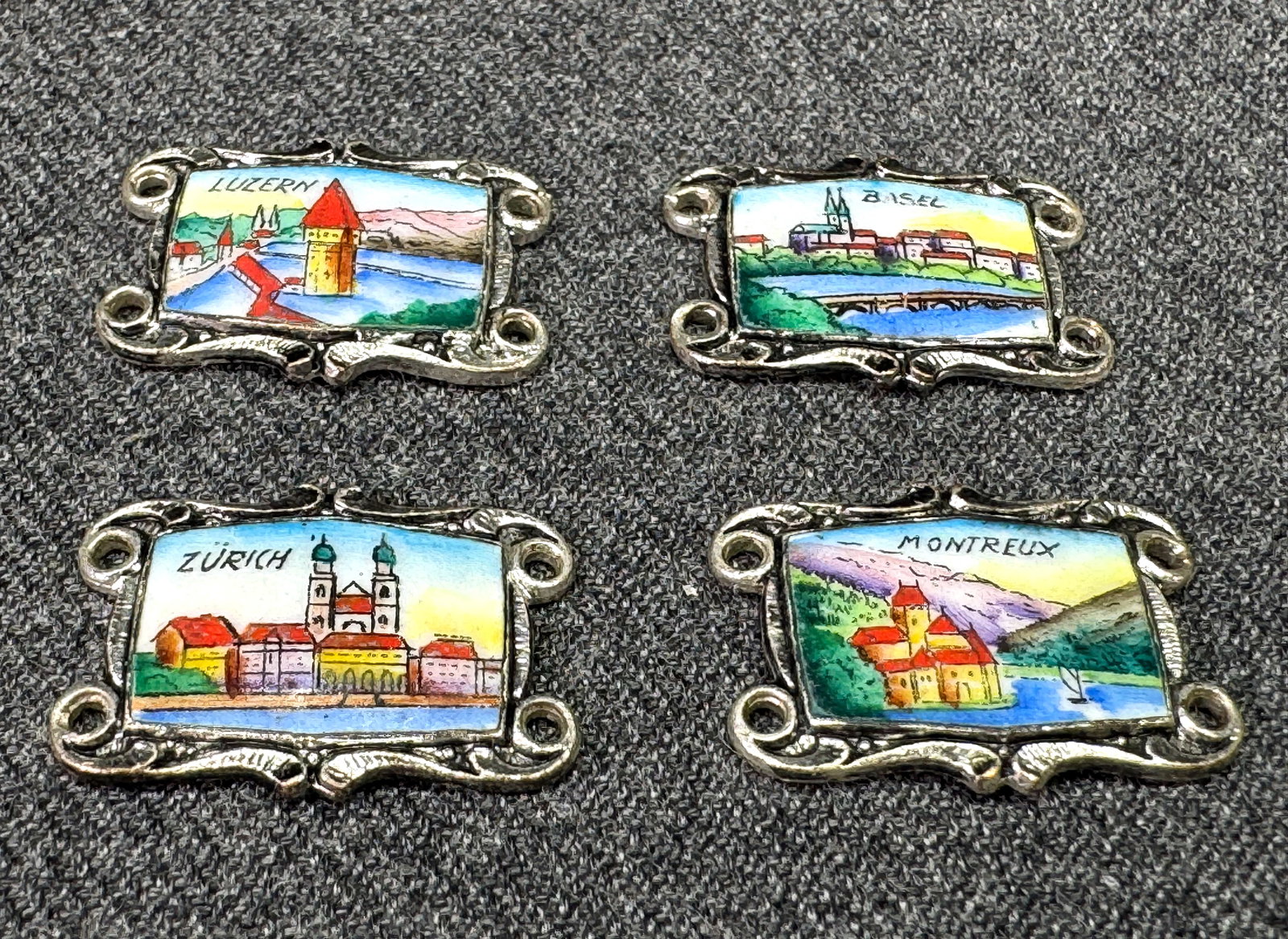 Vintage hand painted enamel Swiss souvenir miniature panels. Silver-toned. Lot of 4. *e: Vintage hand painted enamel Swiss Luzern, Basel, Zurich & Montreux souvenir miniature panels. Silver-toned. Lot of 4. All are Unmarked. For measures please refer to the pictures that were taken with a