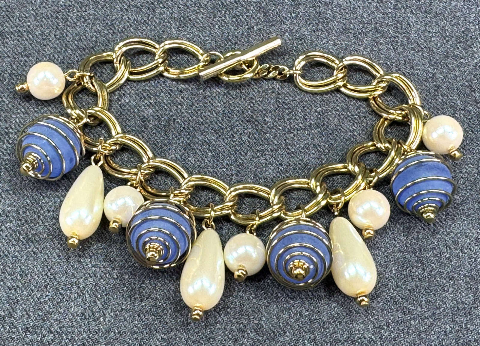 Vintage charms chain bracelet. Pearly & lavender wrapped beads. Gold toned. *e: Vintage charms chain bracelet. Pearly & lavender wrapped beads. Gold toned. Unmarked. For measures please refer to the pictures that were taken with a measuring tape. Weight: 19 Grams. IN HOUSE FLAT S