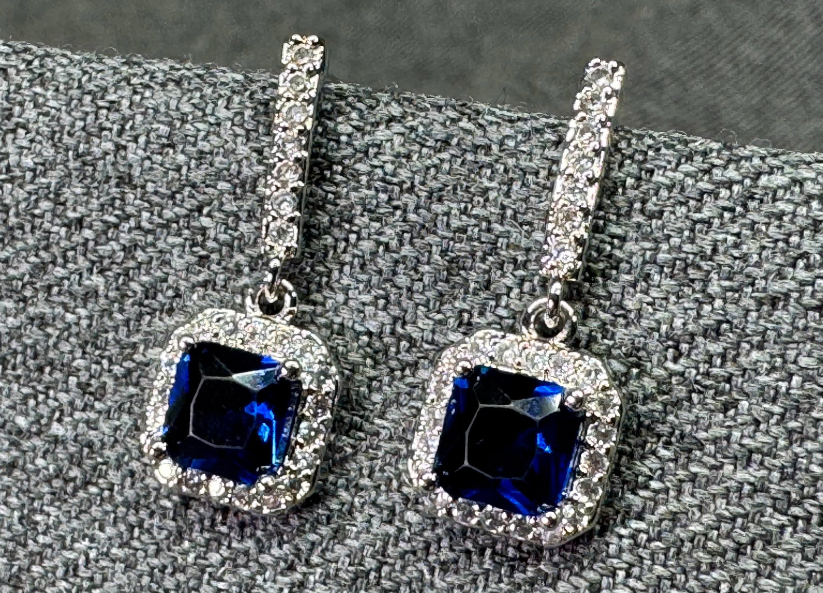 Sterling Silver Simulated Blue Sapphire & Clear CZ Halo Drop Earrings.#n: Sterling Silver Simulated Blue Sapphire & Clear CZ Halo Drop Earrings. Rhodium plated. Marked S925 in post. For measures please refer to the pictures taken with a measuring tape. Weight: 2.25 Grams. I