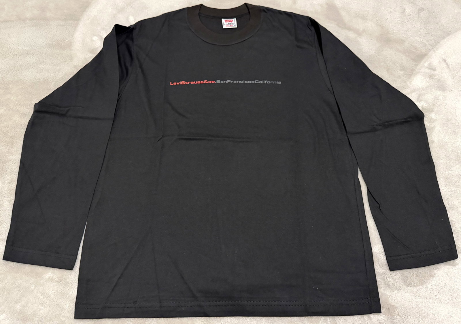 NOS 90s Vintage Levis Long Sleeve Black Spellout Graphic Tee Shirt: Unused "Levi Strauss & Co.San Francisco California" Vintage 1990s minimalist, single-line printed chest graphic in red and white retro typography long-sleeve crewneck t-shirt. 100% Cotton. Official li