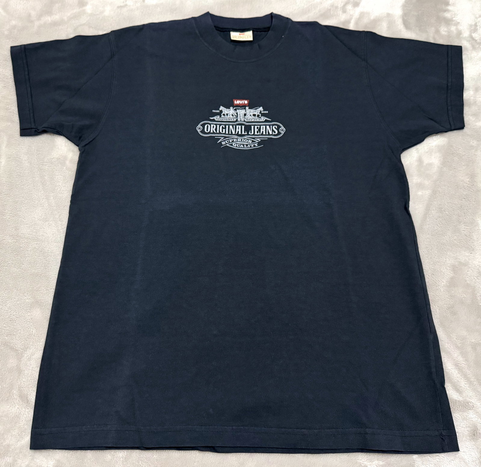 NOS 90s Vintage Levis Navy Blue Two Horse Original Jeans Tee Shirt: Unused Features a classic heritage chest graphic highlighting the historical Levi's two-horse brand mark alongside "Original Jeans" and "Superior Quality" scroll banner typography True vintage 1990s L