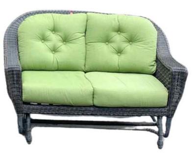 WICKER GLIDER LOVESEAT: Perfect for your sunroom or summer porch, this loveseat style designer faux wicker glider has a french roast finish and comfortable green cushions. In excellent condition, the glider measures approxim