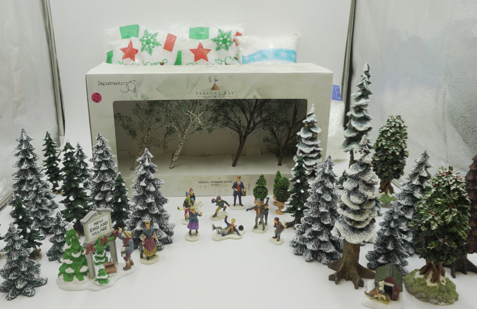 LARGE LOT VARIOUS CHRISTMAS VILLAGE ACCESORIES - 92 PIECES: 92 pieces of various Christmas Village accessories including Mill Creek Pond by Department 56, Seasons Bay Trees by Department 56, plastic snow, and trees in various sizes. Total lot weight is 23 lbs.