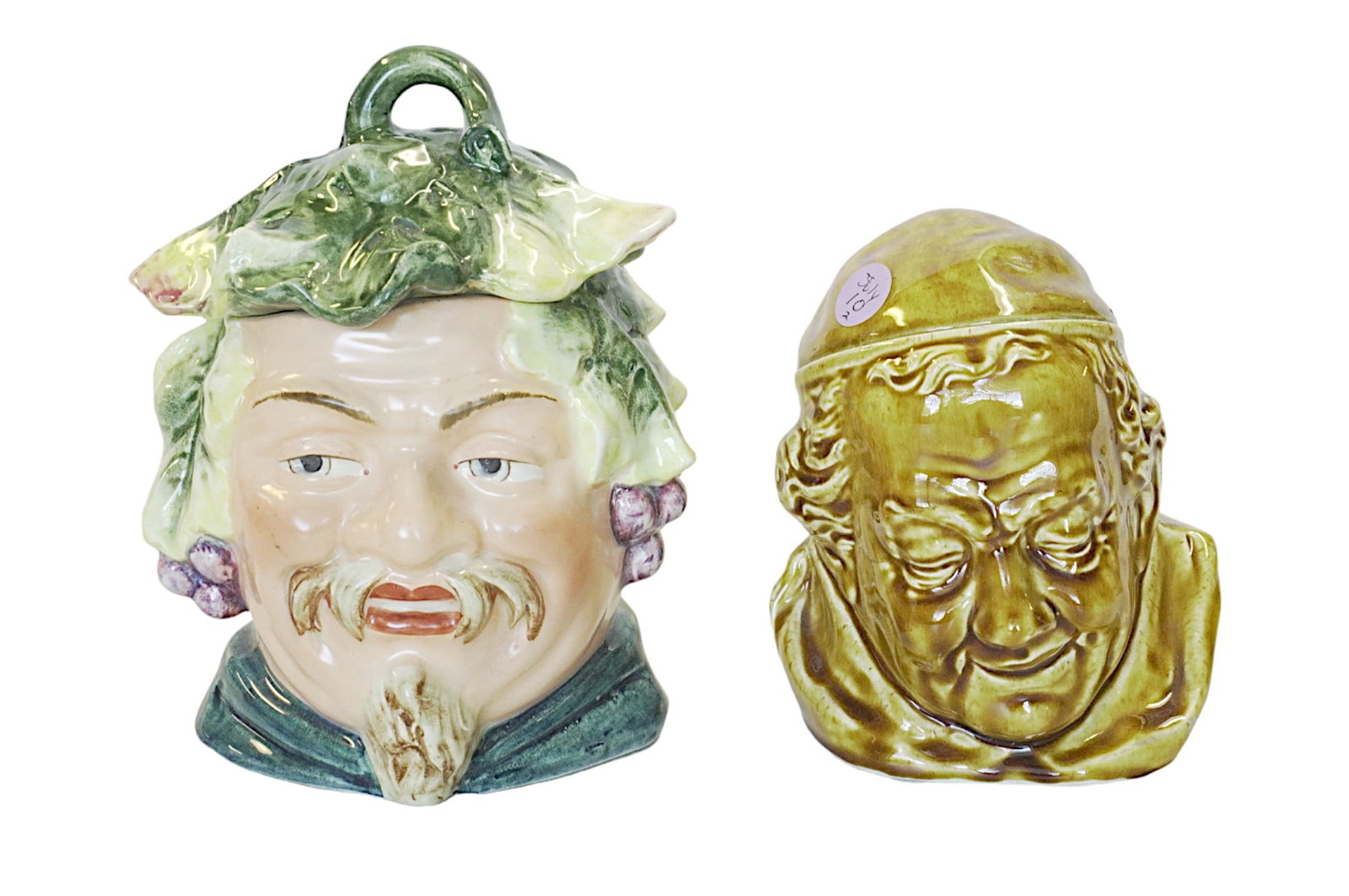 2 MAJOLICA FIGURAL TOBACCO JARS / HUMIDORS: 1- English majolica monks head tobacco jar 6". 2- Large majolica tobacco jar, head of a grinning bearded Bacchus with grapes and leaves at the sides, and with a leaf hat/lid, with faint impressed mark