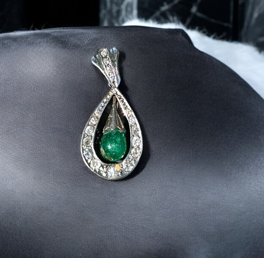 18k TEARDROP EMERALD AND DIAMOND PENDANT: Exquisite ladies 18kt white gold emerald and diamond pendant. The pendant features one cabochon teardrop emerald suspended in the center. The emerald measures approximately 6.65 mm at the base and 8.5
