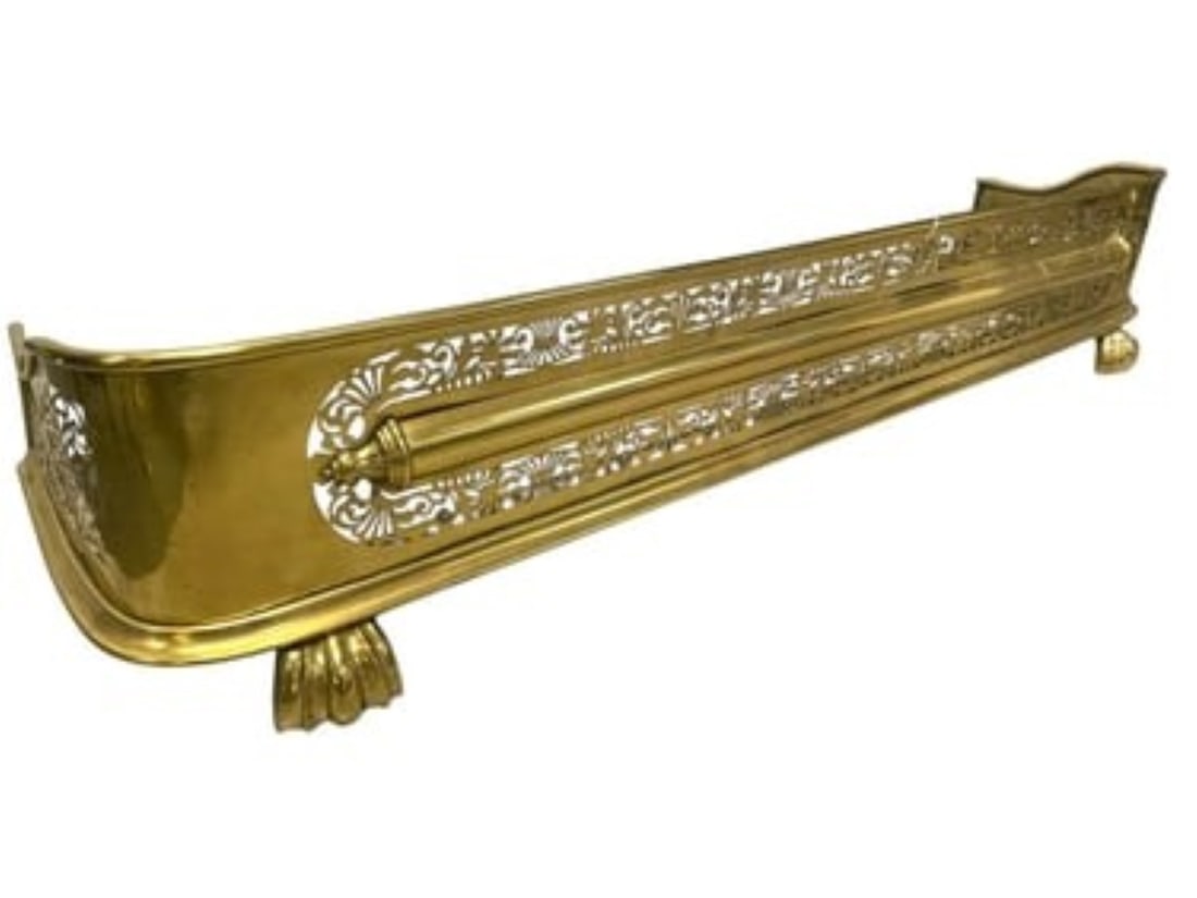 ORNATE ANTIQUE FOOTED BRASS FIREPLACE FENDER: Antique Footed Brass Fireplace Fender with pierced fretwork and armament decoration with a base of claw feet. Measures 47" x 11" x 9.5" and weighs 14 lbs 2 oz.