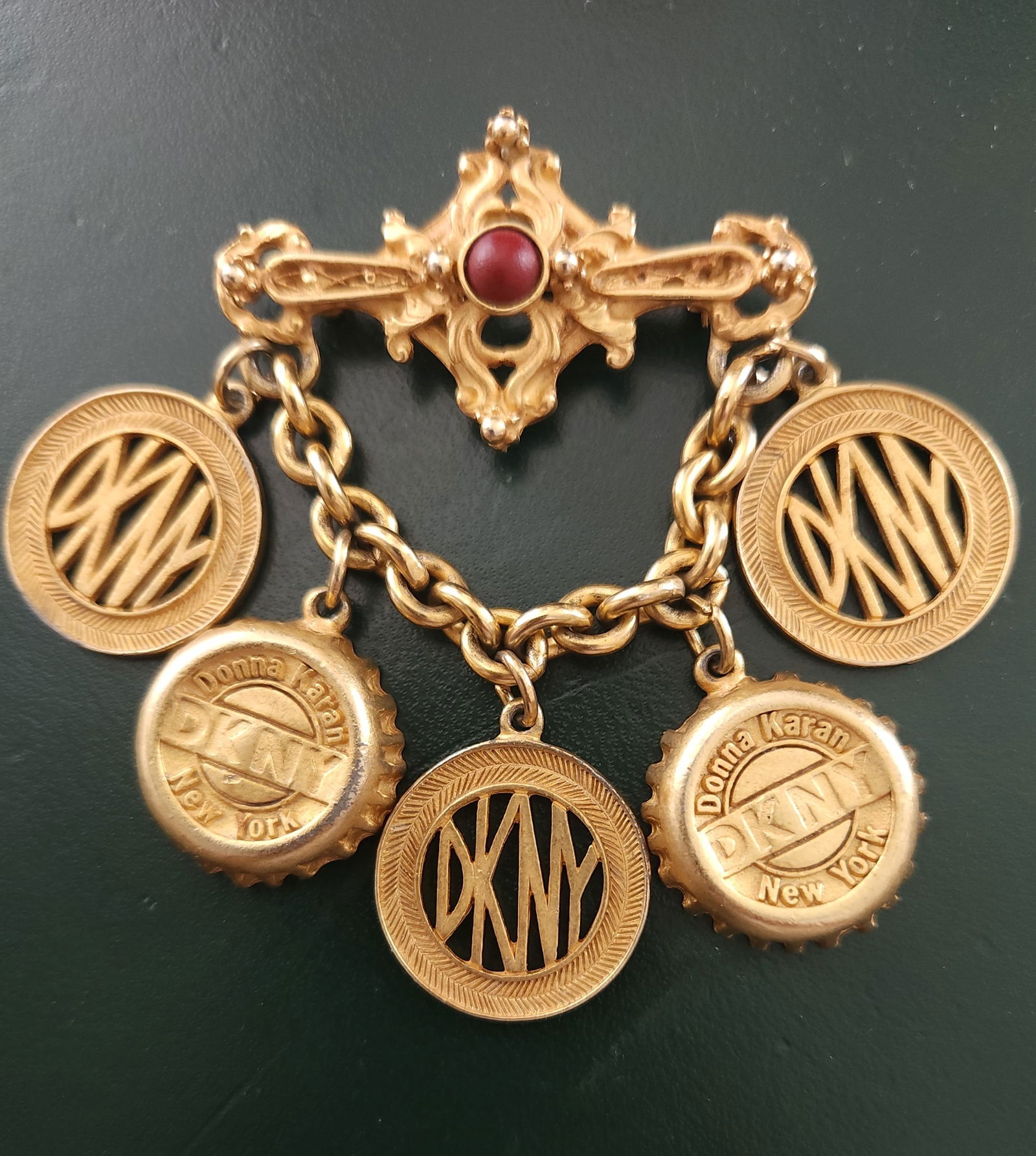 VINTAGE DKNY BOTTLE CAP SUBWAY TOKEN BROOCH: Vintage DKNY Donna Karan Gold Tone Bottle Cap Subway Token Bar Brooch Pin, in very good vintage condition. Measures about 2 7/8" x 2 3/4". Weight 1.5 oz