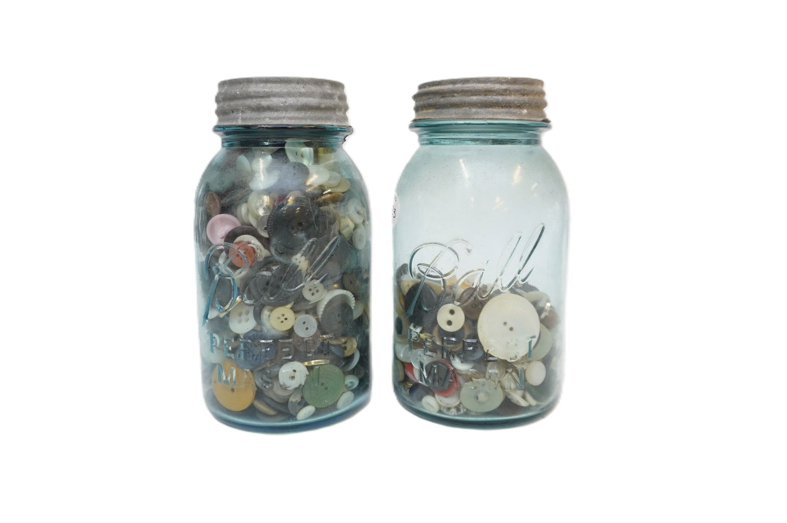 PAIR OF ANTIQUE LIGHT BLUE MASON JARS WITH BUTTONS: Pair of antique (c. 1920s) light blue mason jars. Each measures 7" x 3.75" in dia. Total lot weight is 4 lbs 7 oz. **In house shipping available on this lot**