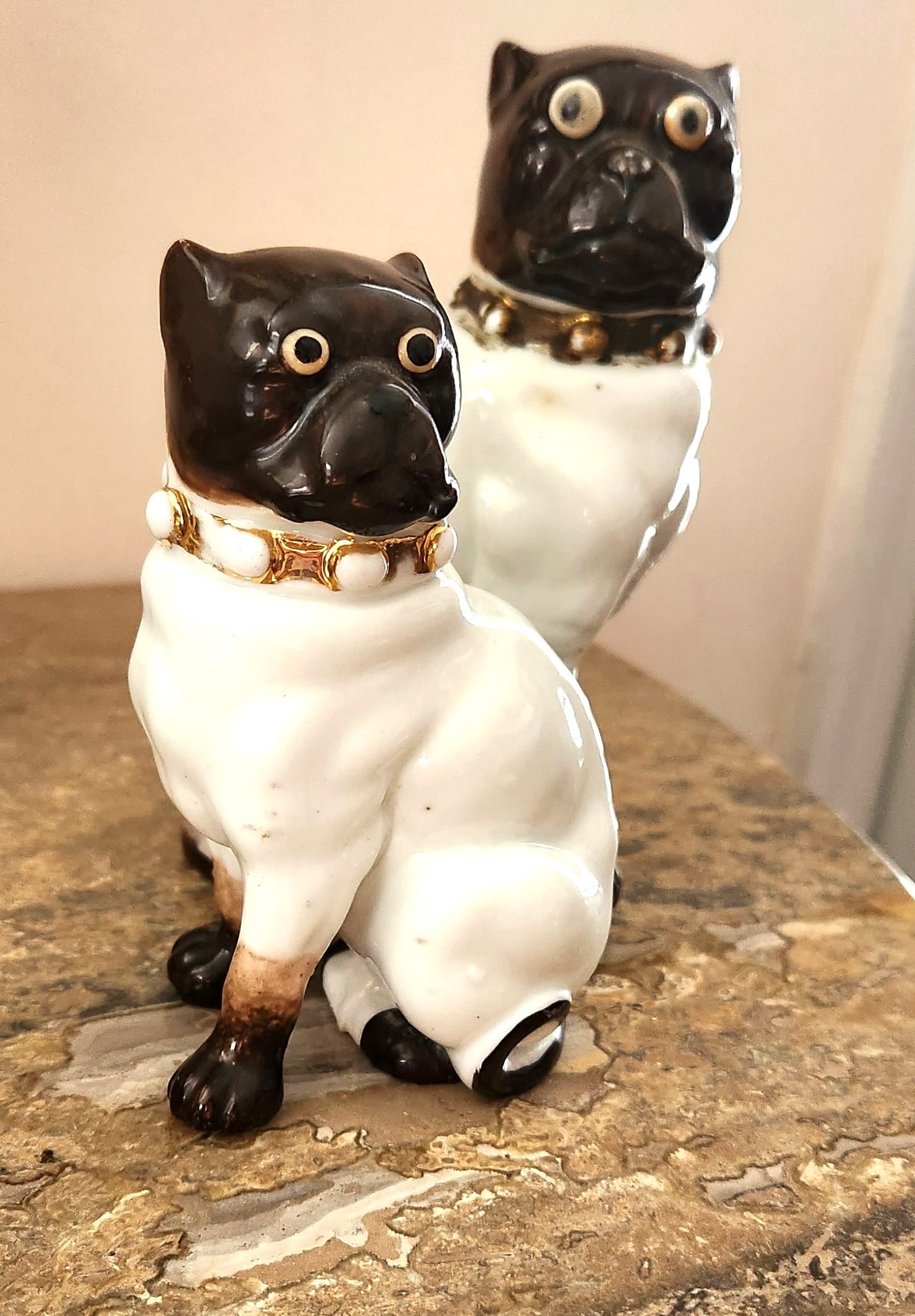 PAIR 19TH C PORCELAIN PUG DOGS: Pair of Late 19th c European Porcelain Seated Pug Dogs, Large 3 1/2"x6". Smaller 3"x4 1/2" Weight 11 oz. In house shipping available on this lot** If you win this lot, please select self arranged for