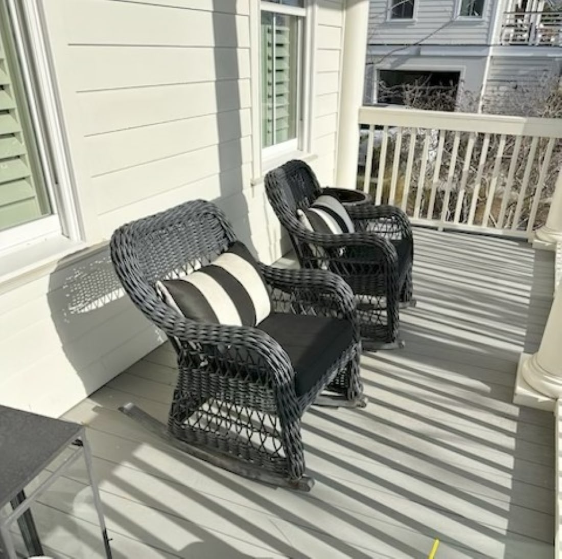 PAIR OF BLACK WICKER ROCKING CHAIRS WITH PILLOWS: Pair of Black Wicker Rocking Chairs with Matching Sunbrella Pillows. Each 36"long 21 1/2" wide and 32 1/2" tall. Provenance: A noted national interior designer