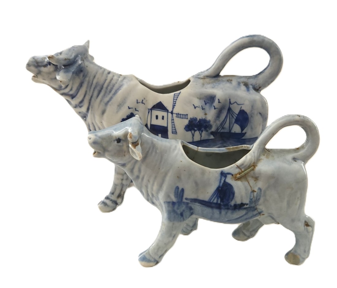 2 ANTIQUE 19th c DELFT COW CREAMERS: 2 Antique 19th c Delft Cow Creamers. Smaller with antique porcelain staple repair. Large 7 3/4"x2"x4 3/4". Small 5 1/2"x1 3/4"x3 1/4". Weight on all 13 oz. **In house shipping available on this lot**