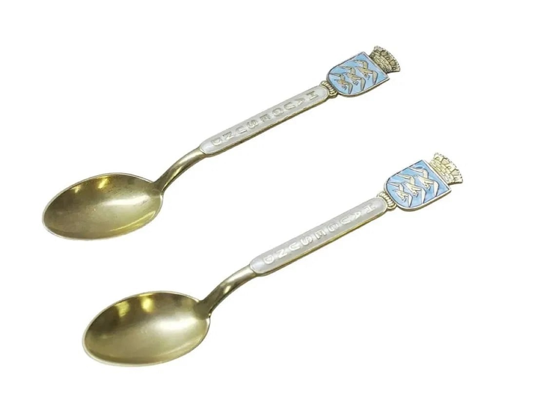 PAIR STERLING GUILLOCHE ENAMEL AKSEL HOLMSEN SPOONS: A pair of Vintage Sterling Silver with Gold Wash Aksel Holmsen Guilloche Enamel Souvenir Demitasse Spoons. Each 4" inch. Approximate silver weight 18 grams. **In house shipping available on this lot**