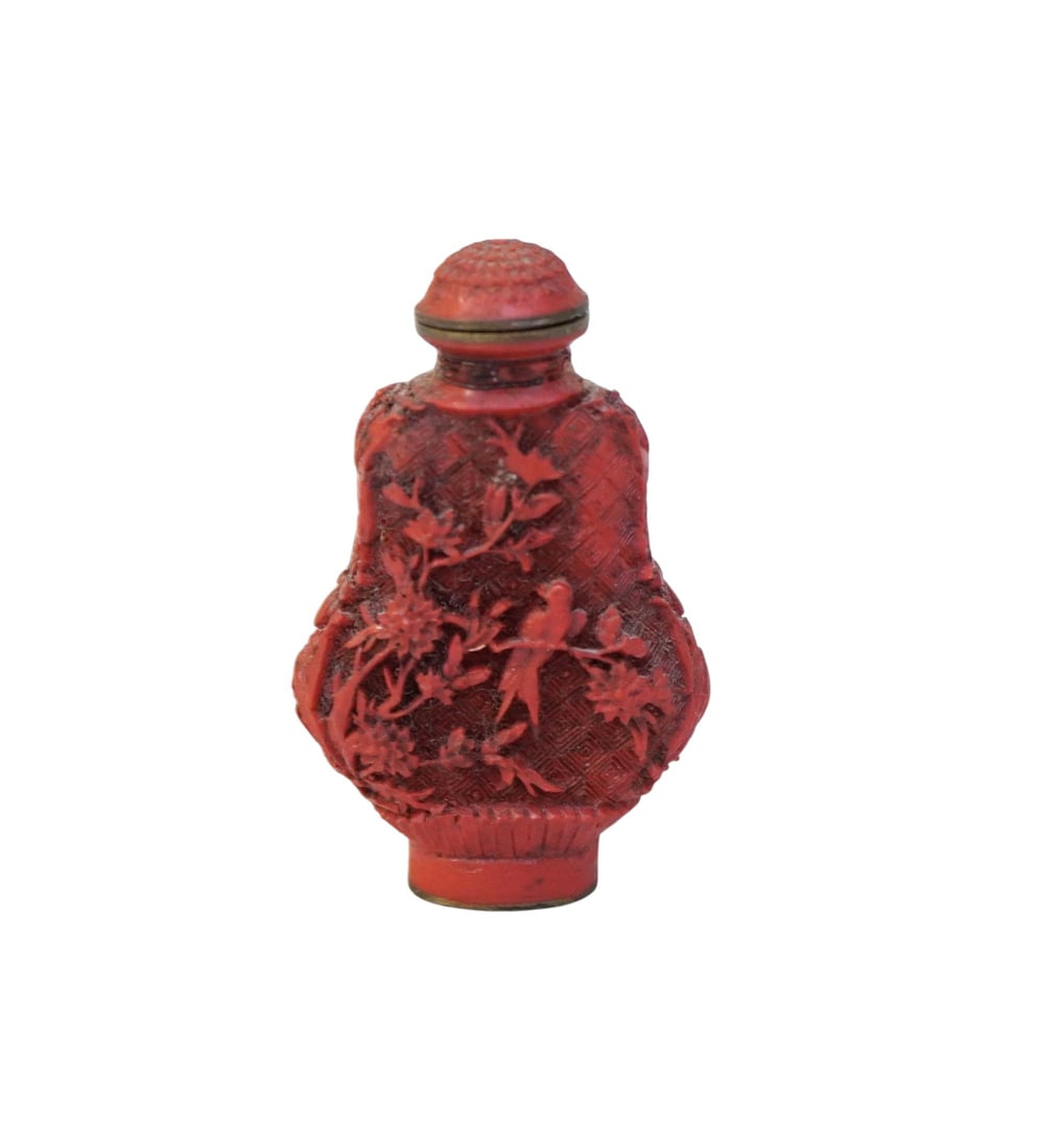 CHINESE CARVED CINNABAR SNUFF BOTTLE: Carved Chinese cinnabar snuff bottle. Hand carved scene of small birds adorned by flowers and foliage. Signed mark on bottom. Top does not open. Measures 2 3/4". Weight 32 grams. Provenance: Gippy Pla