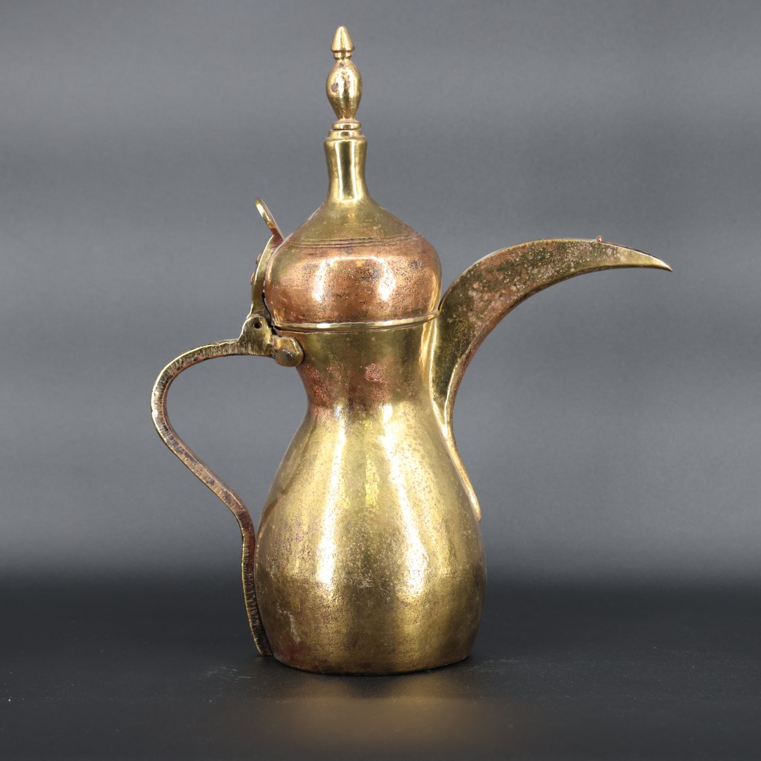 Antique Middle Eastern Brass Dallah Coffee Pot with Finial Lid: Introducing a magnificent antique Middle Eastern brass dallah coffee pot, featuring a beautifully curved spout, an elegant handle, and an ornate finial lid. This exceptional piece is a testament to th
