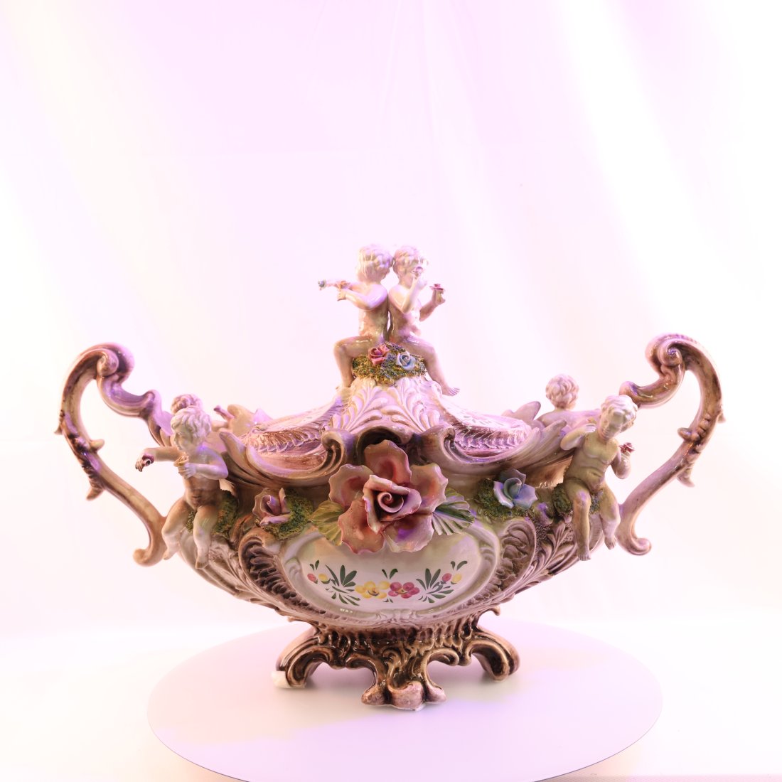 Exquisite Capodimonte Porcelain Centerpiece with Cherubs and Floral Decor: Presenting an elegant Capodimonte porcelain centerpiece, intricately designed with charming cherubs and vibrant floral decorations. This vintage piece showcases the superior craftsmanship Capodimonte