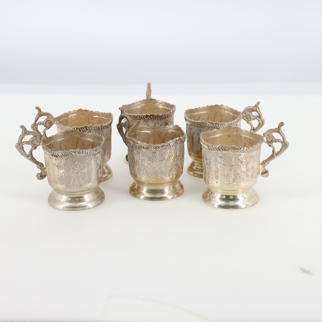 Set of Six Antique Persian Silver Tea Glass Holders: Introducing a beautiful set of six antique Persian silver tea glass holders, each showcasing intricate craftsmanship and elegant design. These holders feature detailed hand-engraved patterns with flor