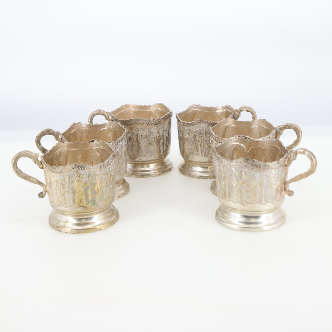 Set of 6 Antique Silver Persian Tea Glass Holders: Introducing a charming set of 6 antique silver Persian tea glass holders, each exquisitely crafted with intricate designs and a rich historical appeal. These holders are a beautiful example of Persian
