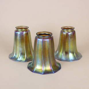 Set of 3 Stueben Gold Aurene Glass Shades: Steuben Glass Works, set of three gold Aurene morning glory ribbed art glass shades with strong iridescence. Each marked with silver fleur de lis stamp inside fitter opening. 5" x 5". Lamp fitter