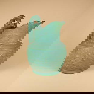 Vance Faience Hound Handle Pitcher: Vance Faience Co. hound handled pitcher with grapes and hunting scene in matte green glaze. Marked only with "84" under base. Tiltonsville, OH. Circa 1902. 10" x 8". This lot ships from our