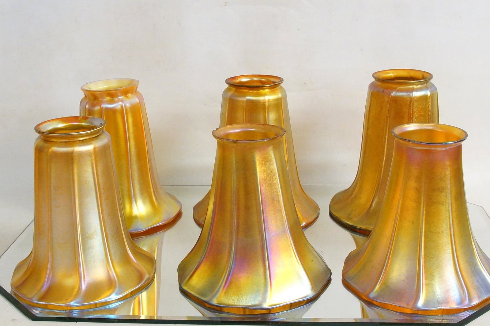 Collection of Quezal iridized glass shades: ribbed and fluted design in a marigold iridized glass color 3 matching pairs measure approx 5.5" high x 5.75"