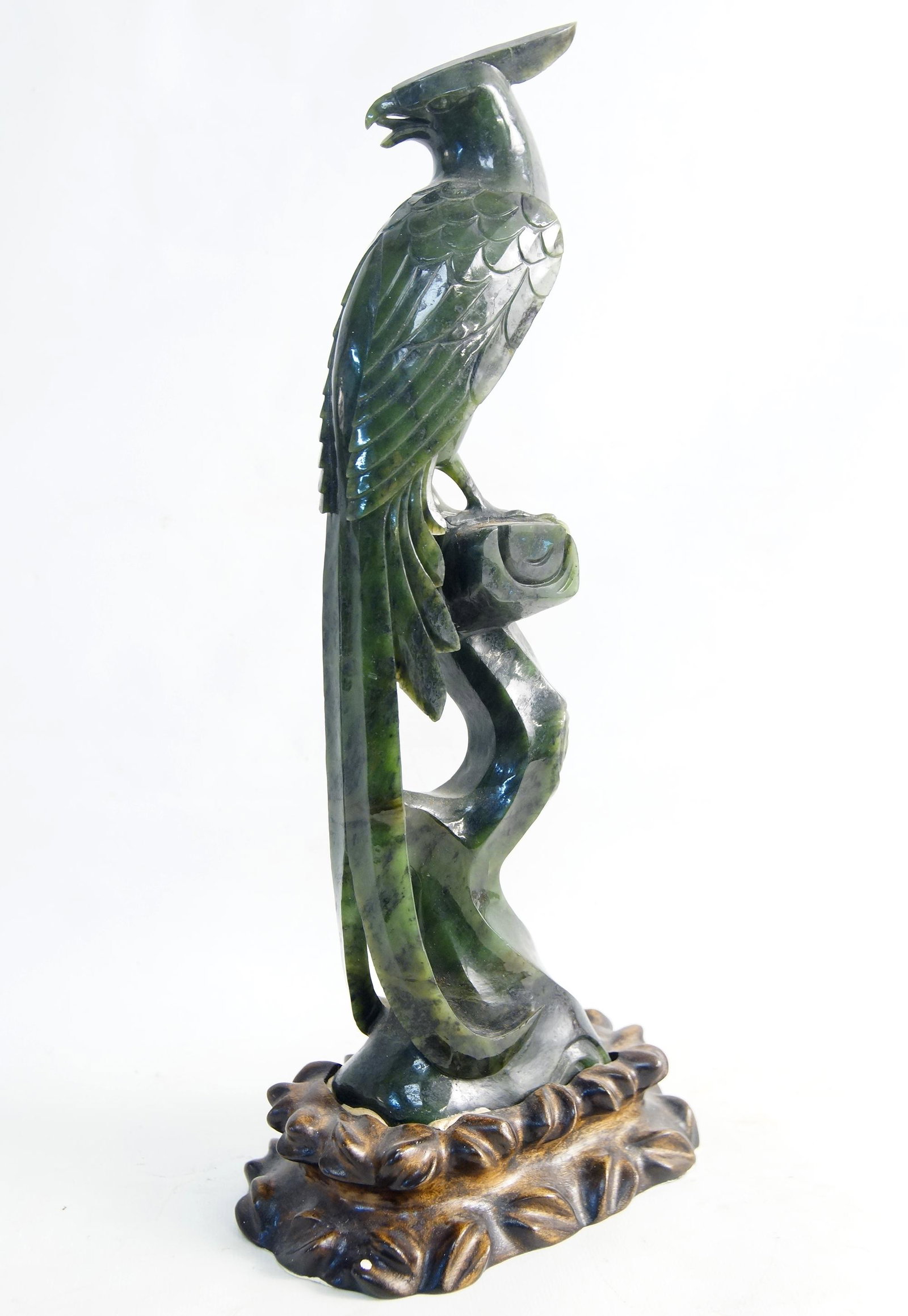 A Fine Spinach Jade Carved Chinese Pheasant: measures 12.75" H and sits upon a 1.5" H wood carved stand. Intricately carved features note the talons and wings - shows restoration at head feather - Provenance: The Estate of Ernest Robert Breech S